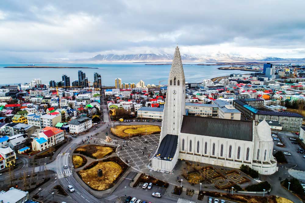 Fly-Fishing-Iceland’s-Blanda-River-with-Joe-Rossi-and-Wildside-Adventures-2 Aerial view of Hallgrímskirkja church in Reykjavik, Iceland, surrounded by colorful buildings, with mountains and water in the background—perfect for those seeking an Arctic Cast and Drift or a Blanda River fishing adventure. | Belize River Lodge Guided Fishing Trips | Wildside Adventures Travel